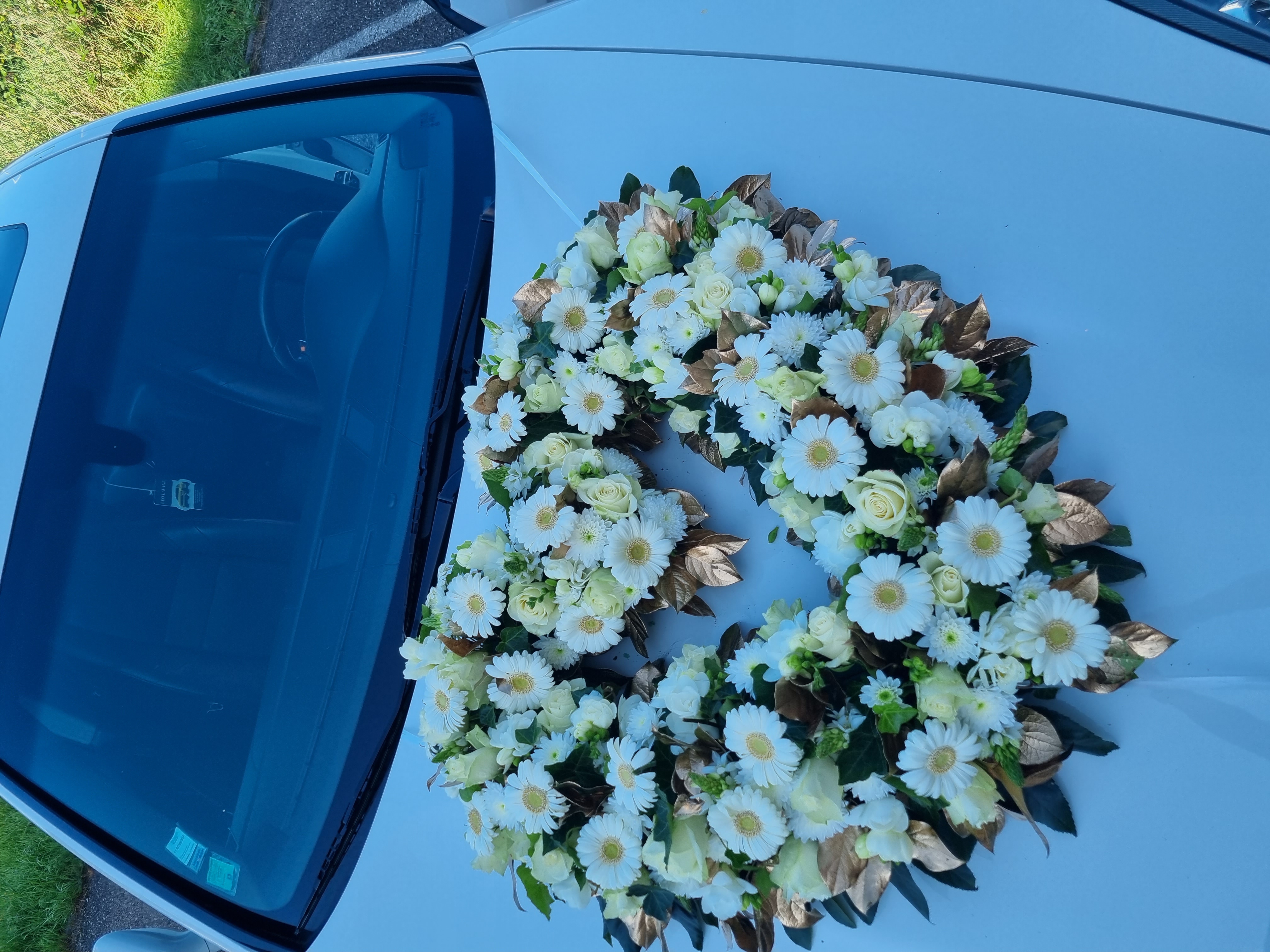 Cœur floral de marguerites sur capot de voiture